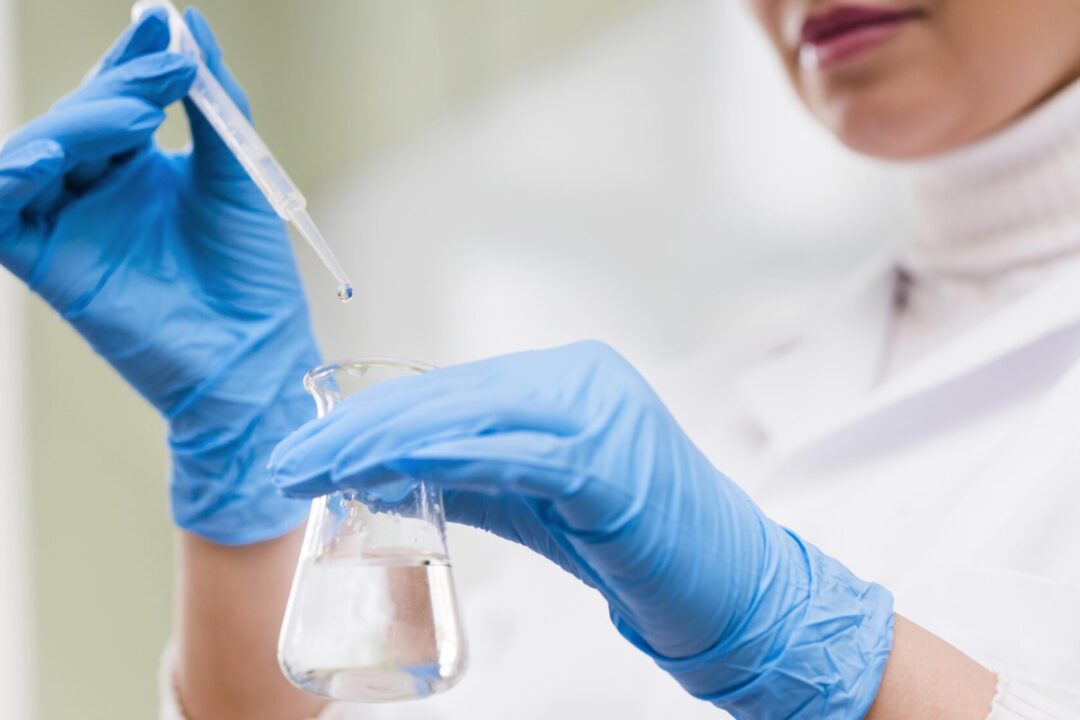 close-up-manos-sosteniendo-pipeta-y-vidrio